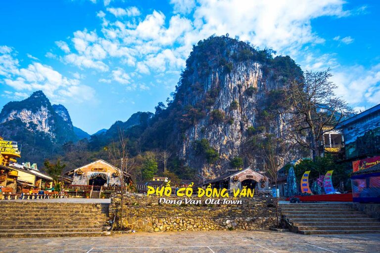 Ingang van Dong Van Old Quarter met marktplaats en steile kalksteenbergen erachter.