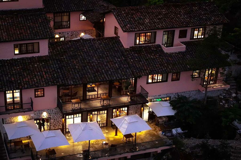 Avondzicht op Ha Giang Aya Lodge, met warm verlichte terrassen en traditionele architectuur midden in de bergen.