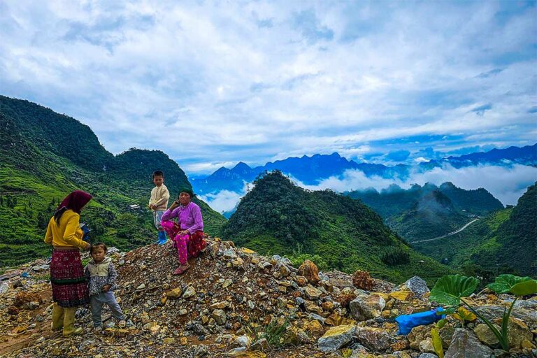 Hmong-kinderen lopend over bergpad met grillige karsttoppen en terrassen langs de Ha Giang Loop.