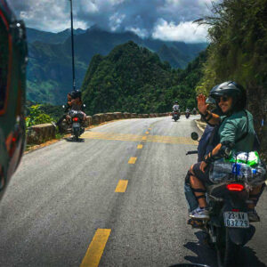Reizigers op een Easy Rider motorbiketocht langs de Ha Giang Loop, rijdend door hoge bergpassen met panoramisch uitzicht.