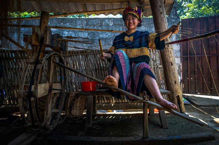 Hmong-vrouw in Lung Tam die handgesponnen draden maakt bij traditioneel weefgetouw