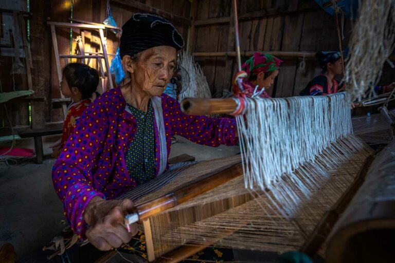 Vrouw uit Lung Tam die traditioneel linnen weeft op een houten weefgetouw