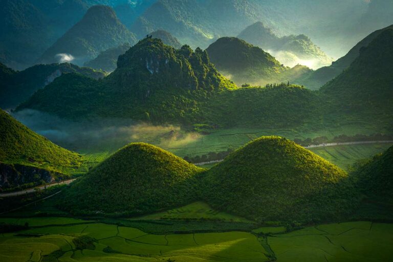 Landschap rond de Quan Ba Twin Mountains met ochtendlicht over groene heuvels.
