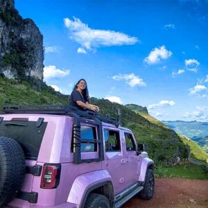 Reiziger zit bovenop een roze jeep tijdens een Ha Giang Loop jeep tour met panoramisch uitzicht over de bergvallei.