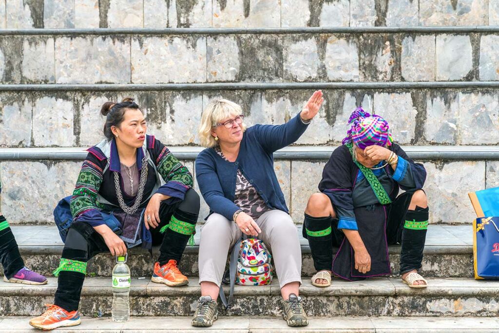 een 60+ tourist zit op een trap met etnische minderheden in Sapa Vietnam