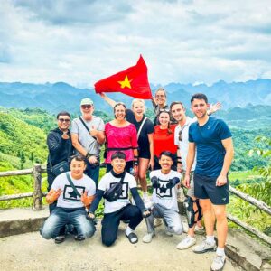Nederlandse en Belgische reizigers tijdens een Ha Giang Loop Easy Rider tour poseren als groep bij een spectaculair uitzichtpunt met Local Vietnam-gidsen en de iconische bergen op de achtergrond.