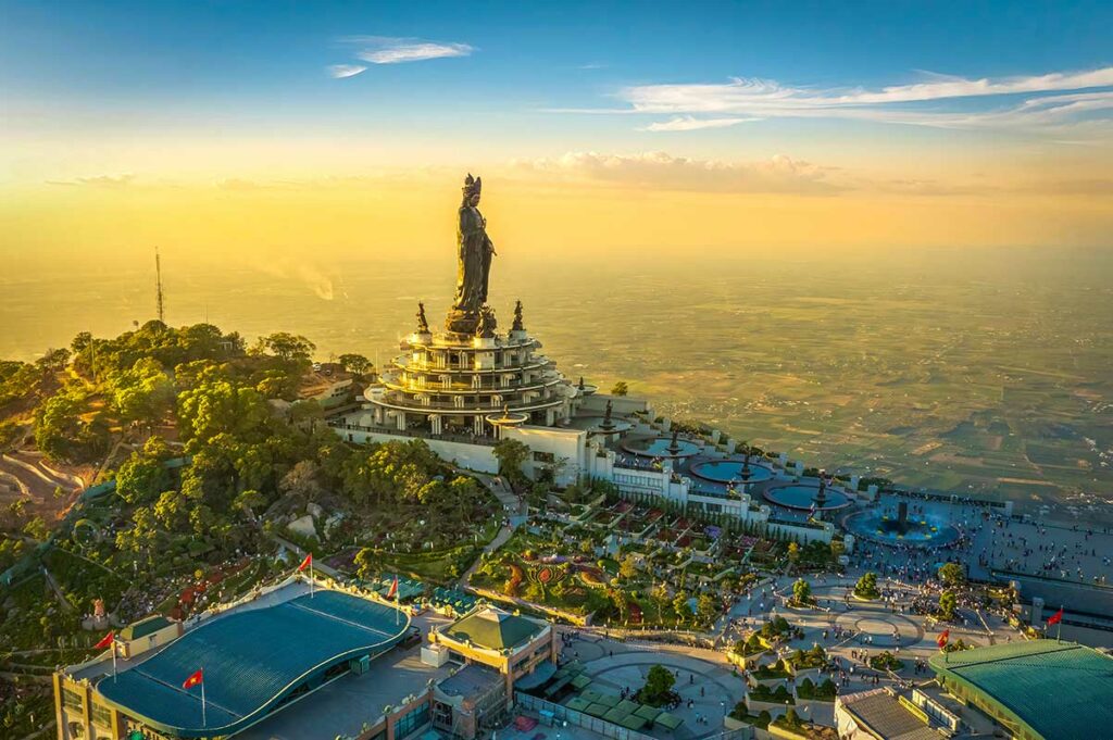 Overzicht van Ba Den Mountain (Black Virgin Mountain) met het grote Bodhisattva-beeld en het tempelcomplex bij zonsondergang