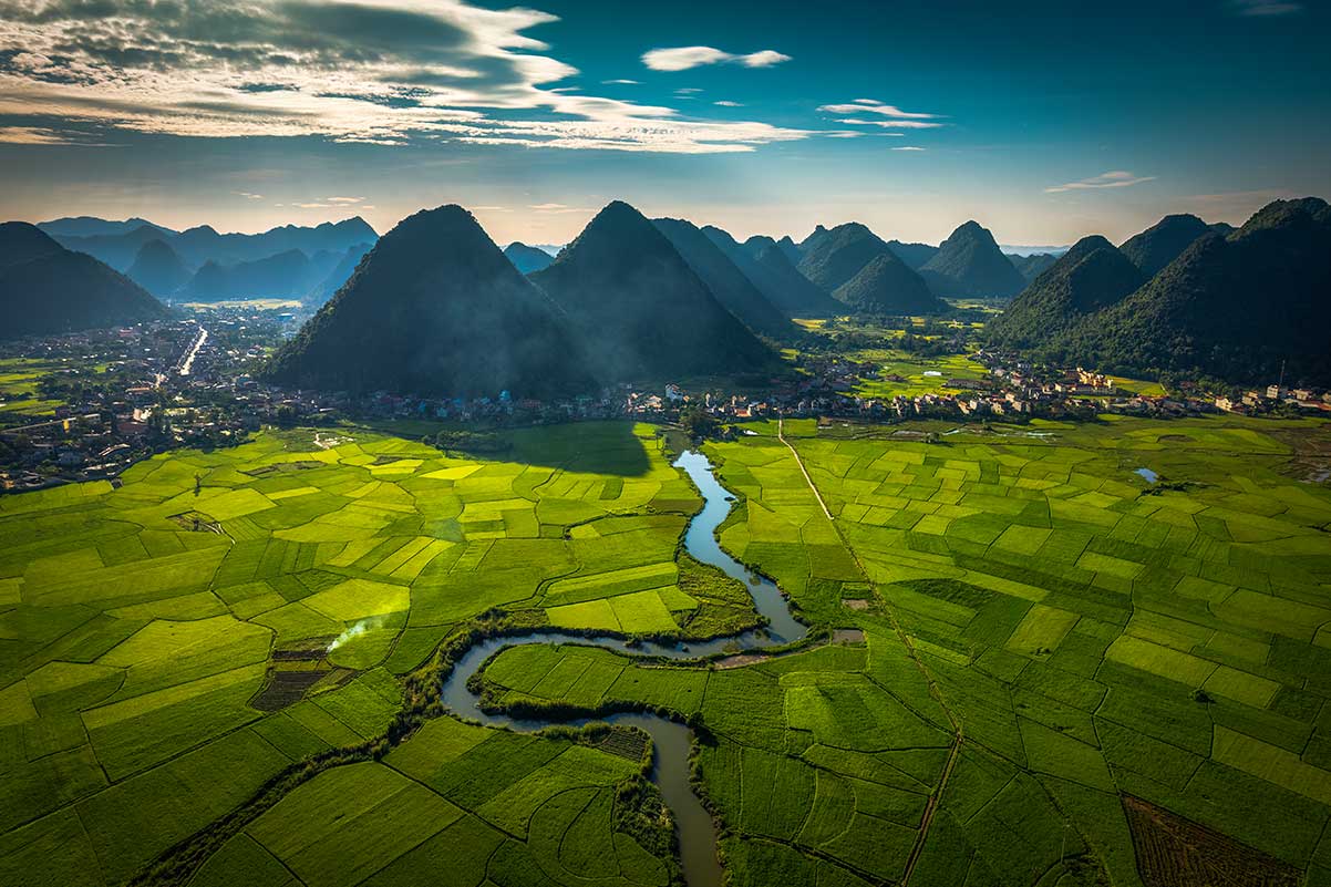 Landschap van de Bac Son Valley in Vietnam met rijstvelden, kronkelende rivier en karstbergen