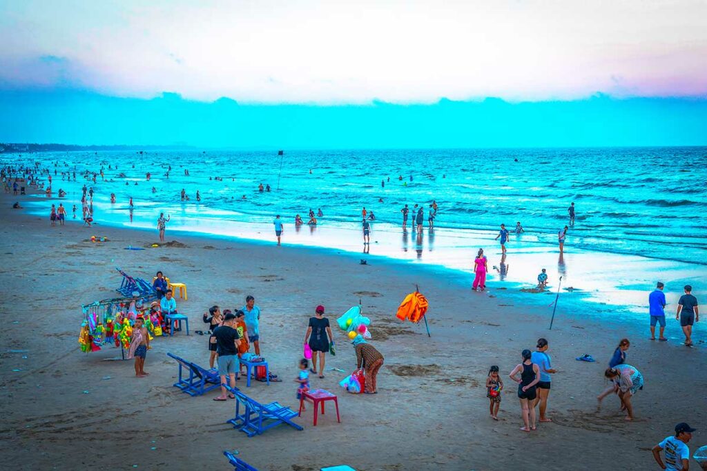 Drukte op Back Beach in Vung Tau, met lokale families en bezoekers die zwemmen en ontspannen aan zee