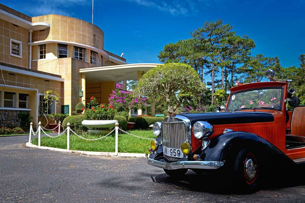 Buitenkant van het Bao Dai Summer Palace in Da Lat, voormalige residentie van keizer Bao Dai, met Franse koloniale architectuur en een klassieke auto op de voorgrond.