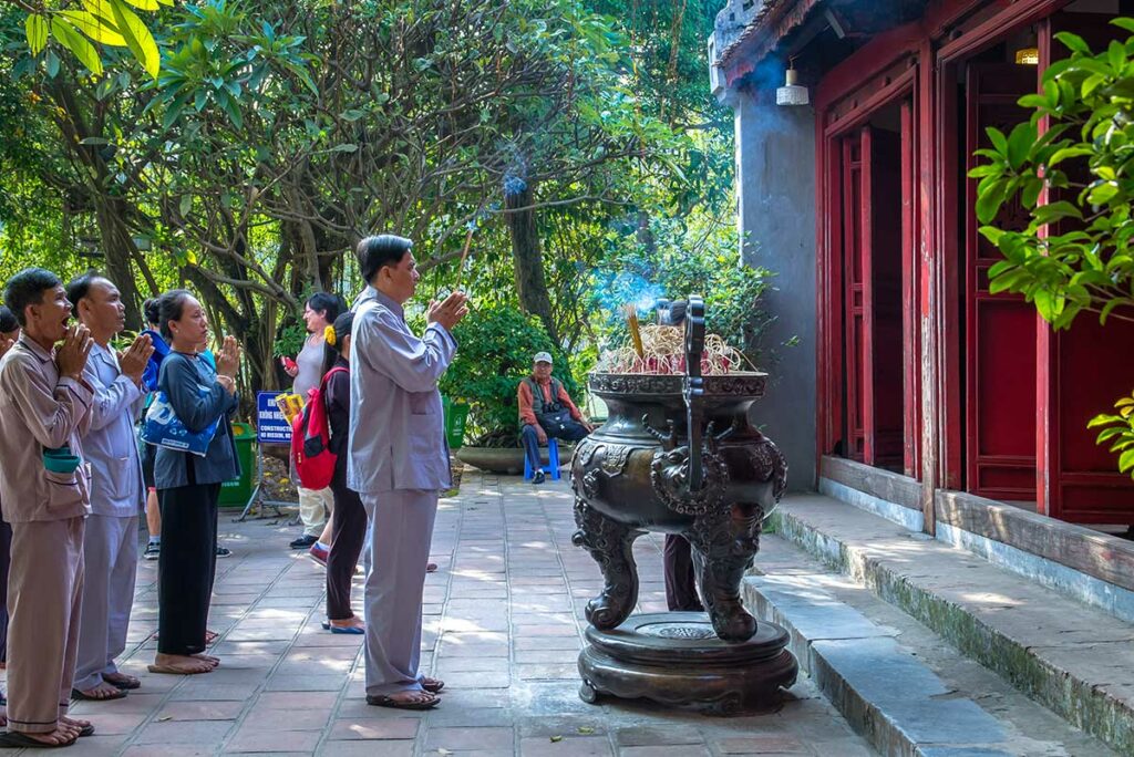 Lokale bewoners die wierook branden en bidden bij de Ngoc Son-tempel aan het Hoan Kiem-meer in Hanoi