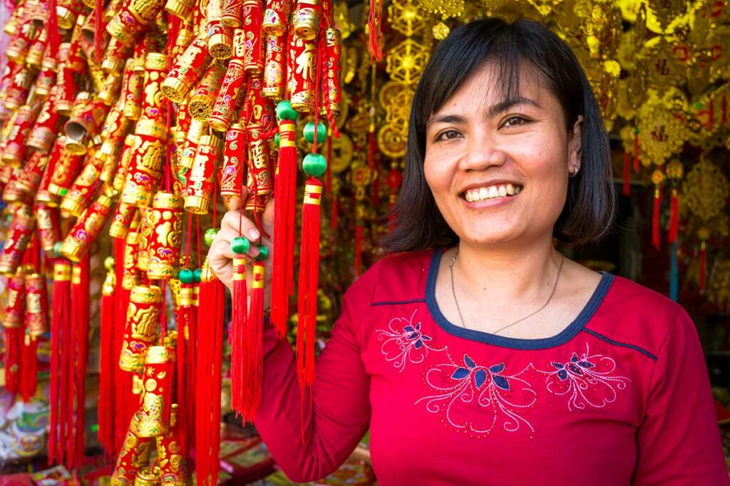 Verkoopster bij Binh Tay Market met traditionele Chinese decoraties en rood-gouden hangers, typerend voor Chinatown in Ho Chi Minh City.