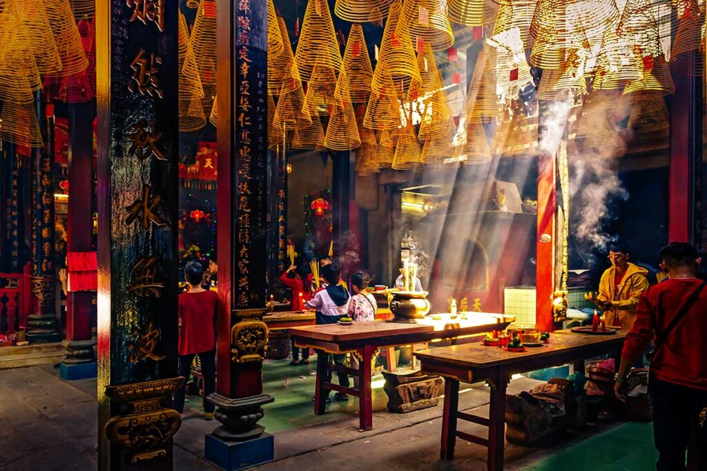 Bezoekers die bidden in Thien Hau Pagoda in Chinatown, met grote wierookspiralen en offeraltaars in de tempelhal.