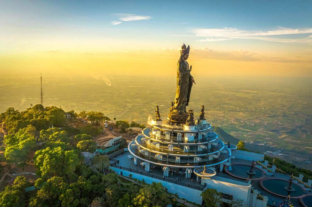 Bodhisattva-beeld op Ba Den Mountain bij zonsondergang, met uitzicht over Tay Ninh en het omliggende platteland