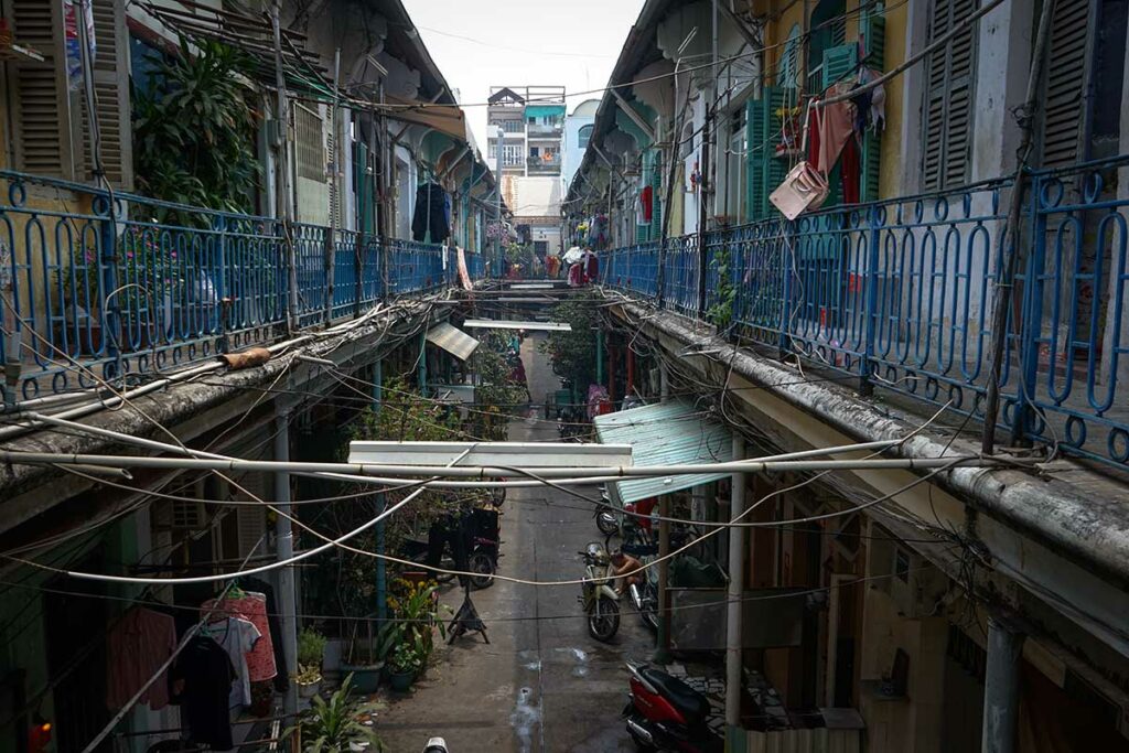 Smalle steeg in Hao Si Phuong Alley in Chinatown Ho Chi Minh City, met oude appartementen, balkons en zichtbare elektriciteitskabels.