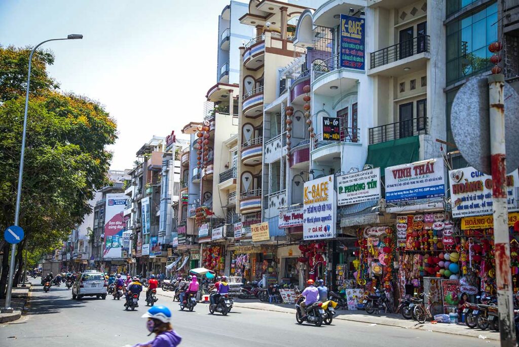 Straatbeeld in Chinatown Ho Chi Minh City met woonhuizen, winkels en veel scooters, typisch voor het dagelijkse leven in Cho Lon.