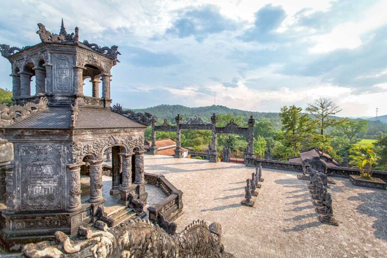 Eerhof van de Tombe van Khai Dinh met het achthoekige stèlepaviljoen, stenen beelden en uitzicht over de heuvels rond Hue.