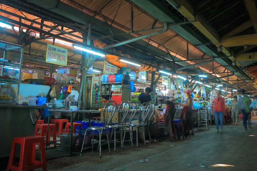 Eenvoudige foodcourt bij Binh Tay Market waar locals eten bij kleine streetfoodkraampjes in de overdekte markthal.