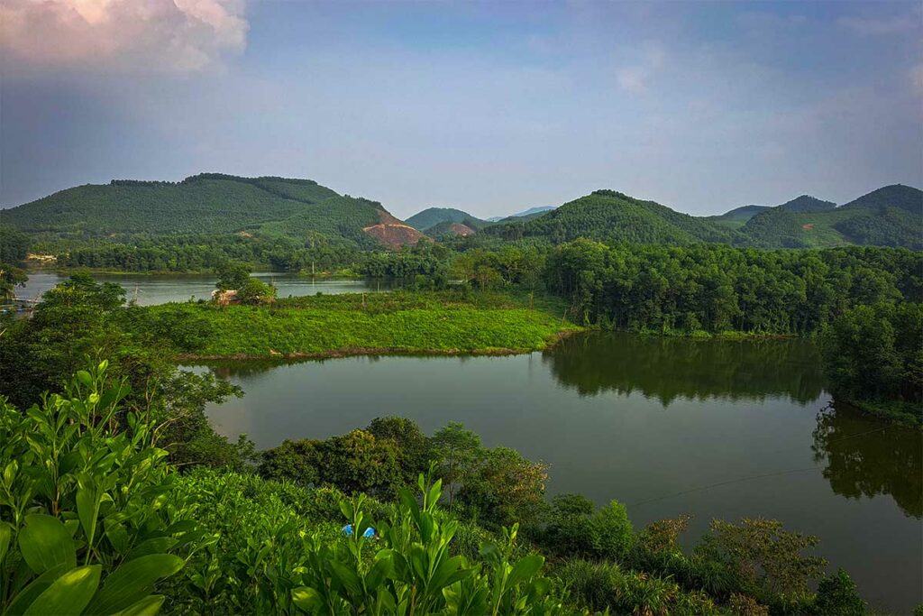 Ghenh Che Lake in Thai Nguyen met rustig water, groene oevers en heuvels op de achtergrond