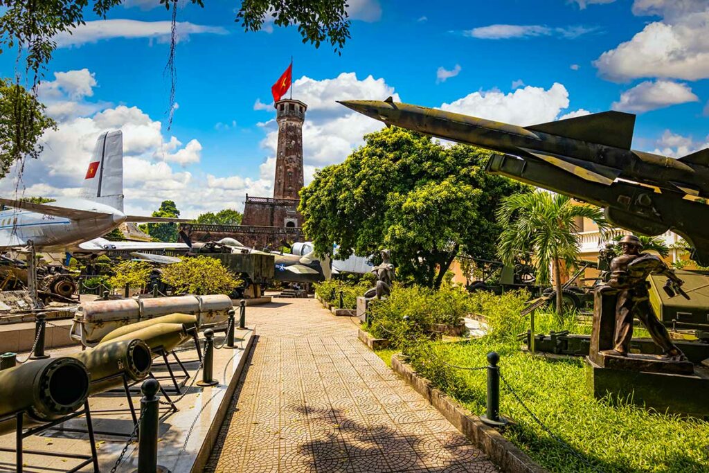Hanoi Flag Tower gezien vanaf het terrein van het voormalige Vietnam Military History Museum, met militaire vliegtuigen en raketten op de voorgrond