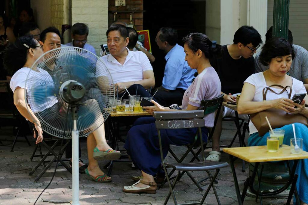 Lokale bewoners zitten buiten bij een café in Hanoi tijdens een warme en benauwde zomerdag