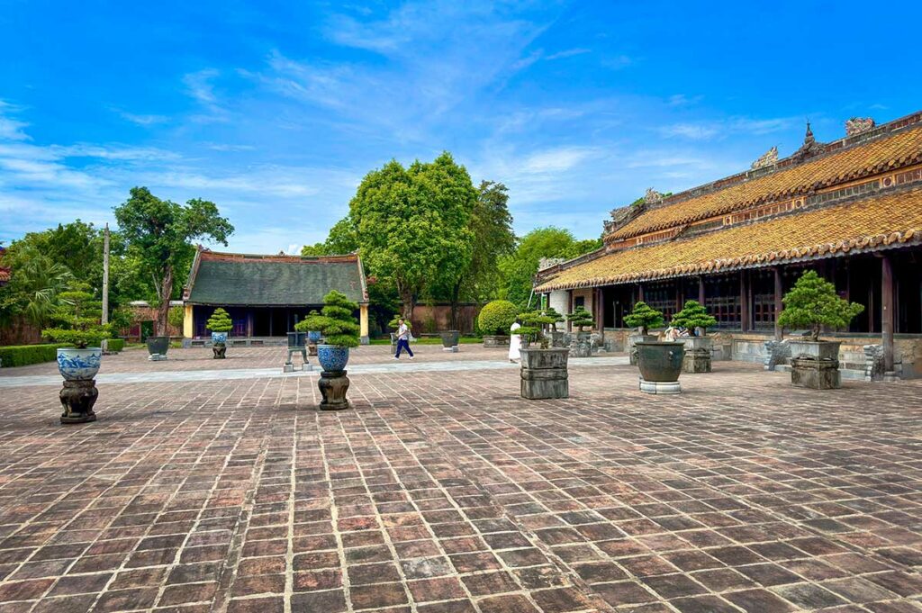 Binnenplaats van de Hoa Khiem-tempel bij de tombe van keizer Tu Duc, met traditionele gebouwen, bonsaibomen en open plein in het hart van het complex.