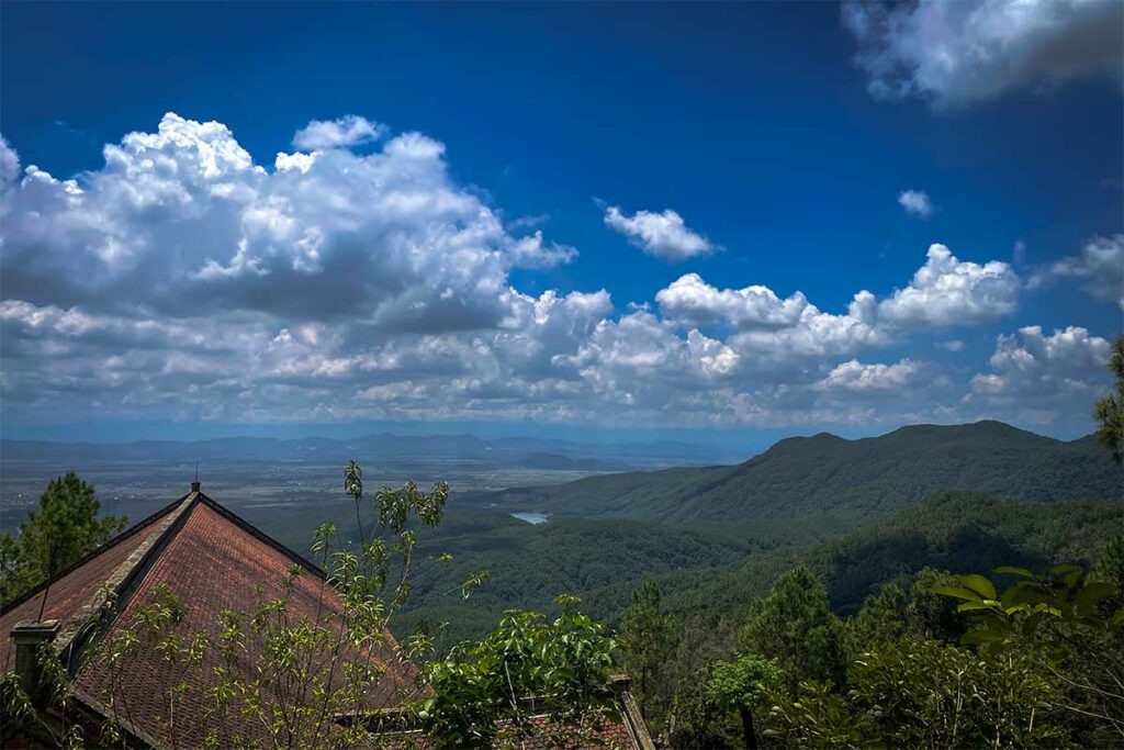 Uitzicht vanaf de Huong Tich-pagode over beboste heuvels en laagland rond Vinh, gelegen in een rustig natuurgebied.