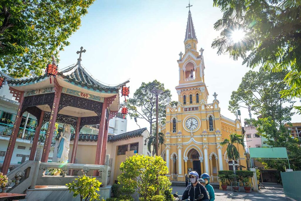 Cha Tam Church (St. Francis Xavier Church) in Chinatown Ho Chi Minh City, met op de voorgrond een Chinese tempel en lokaal verkeer.
