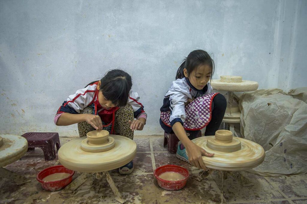 Kinderen volgen een pottenbakworkshop en leren werken met klei in Bat Trang Pottery Village