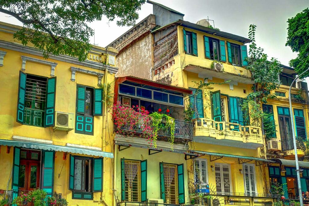 Geel geschilderde koloniale huizen met groene luiken in de Franse wijk (French Quarter) van Hanoi