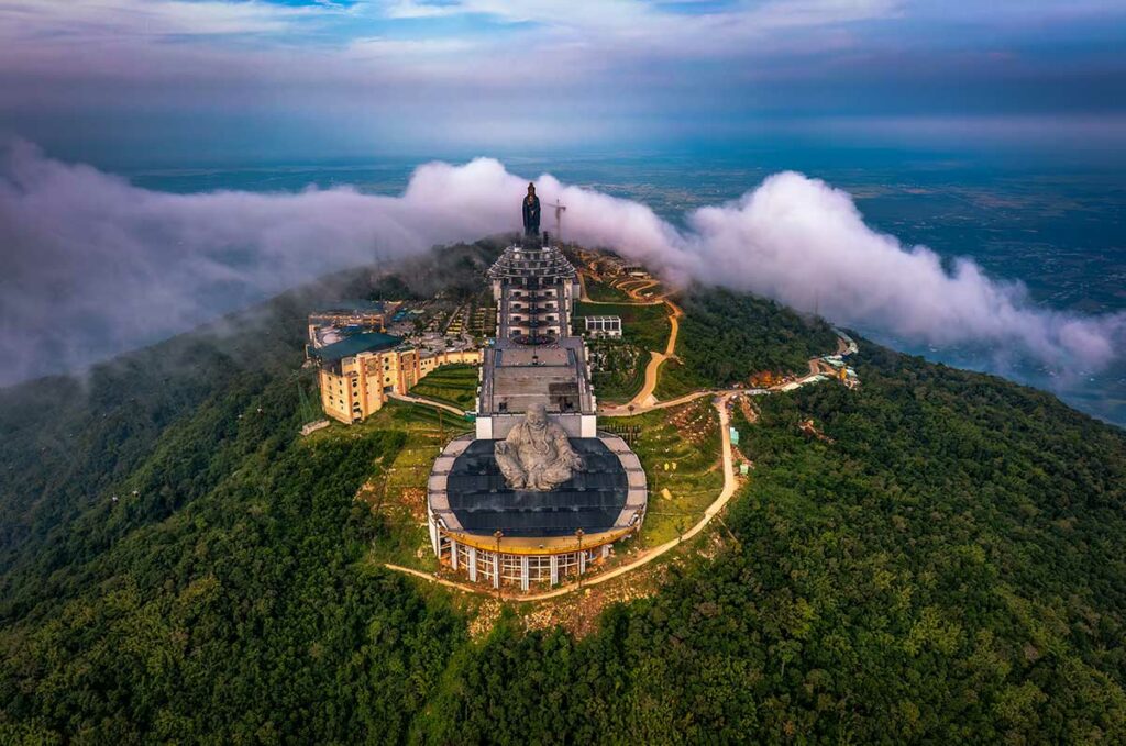 Luchtfoto van het tempelcomplex en het Bodhisattva-beeld op de top van Ba Den Mountain, omringd door bos