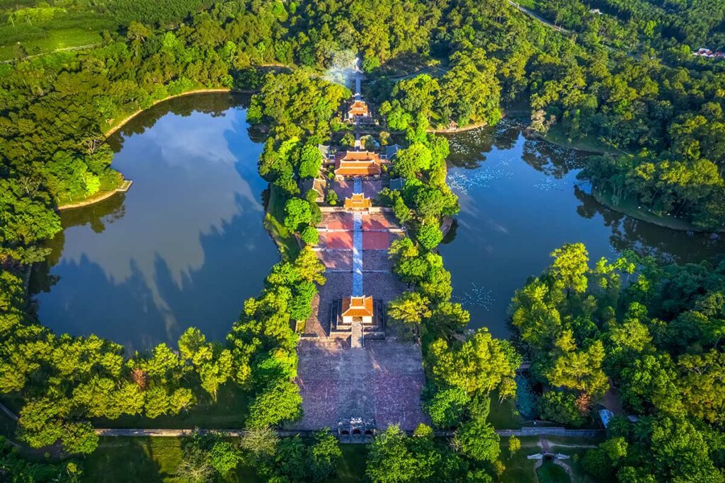 Luchtfoto van de tombe van keizer Minh Mang bij Hue, met de symmetrische opzet, meren, paviljoens en het centrale pad door het groene landschap.