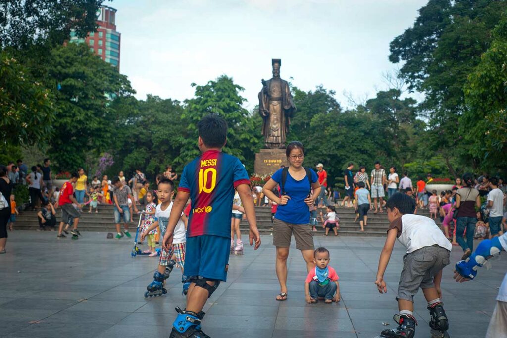 Lokale gezinnen en kinderen in Ly Thai To Park in Hanoi, met het standbeeld van koning Ly Thai To op de achtergrond