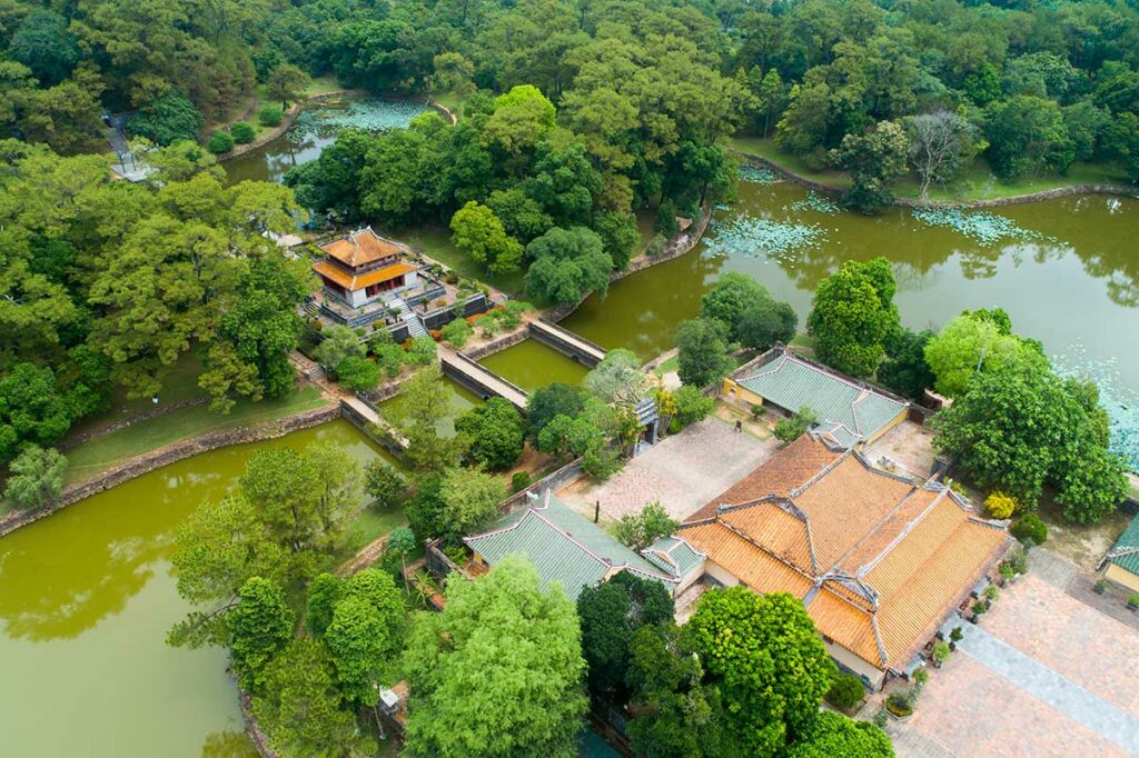 Luchtfoto van de tombe van keizer Minh Mang met meren, bruggen, paviljoens en paleizen die symmetrisch in het landschap zijn aangelegd.