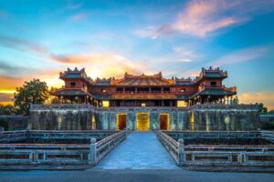 Monumentale toegangspoort van de Imperial City of Hue, het keizerlijke hart van de Nguyen-dynastie, gezien bij zonsondergang met symmetrische brug en stadsmuren.
