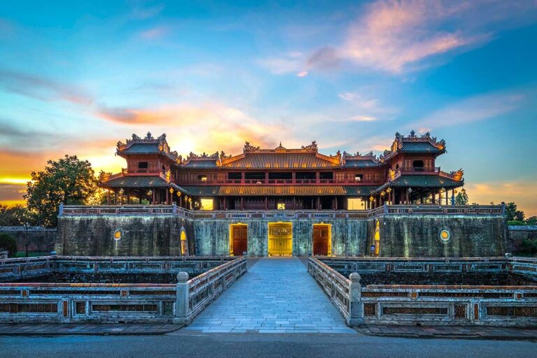 Monumentale toegangspoort van de Imperial City of Hue, het keizerlijke hart van de Nguyen-dynastie, gezien bij zonsondergang met symmetrische brug en stadsmuren.