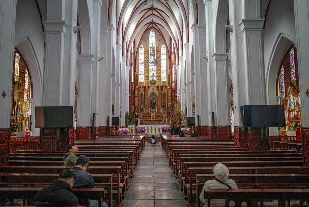 Interieur van St. Joseph’s Cathedral in Hanoi met lange houten banken en hoge gewelven