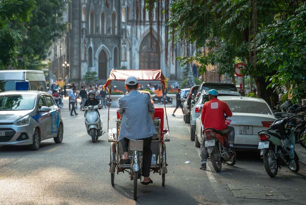 Cyclo in de Franse wijk van Hanoi met St. Joseph’s Cathedral zichtbaar op de achtergrond