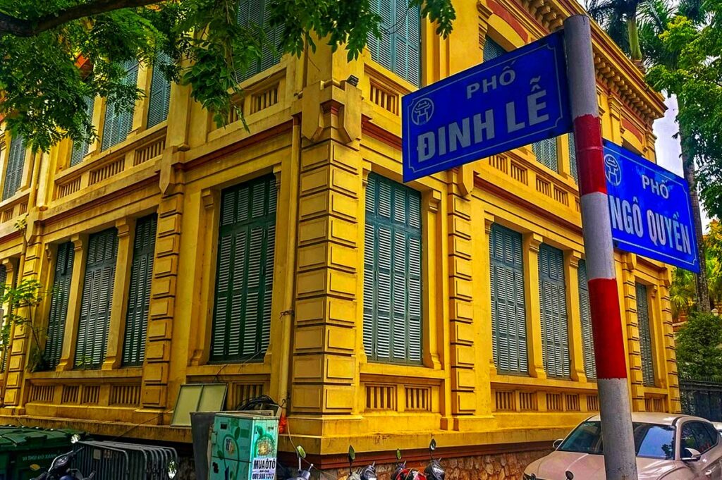 Straat in de Franse wijk van Hanoi met geel geschilderde koloniale panden en groene luiken