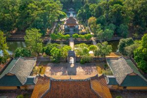 Overzicht van de tombe van keizer Minh Mang in Hue, gezien vanaf de centrale as met tempels, poorten en waterpartijen in een bosrijke omgeving.