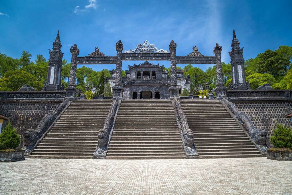 Steile trap met drakenpilaren die leidt naar het bovenste terras van de Tombe van keizer Khai Dinh, gebouwd tegen de heuvel van Chau Chu Mountain.