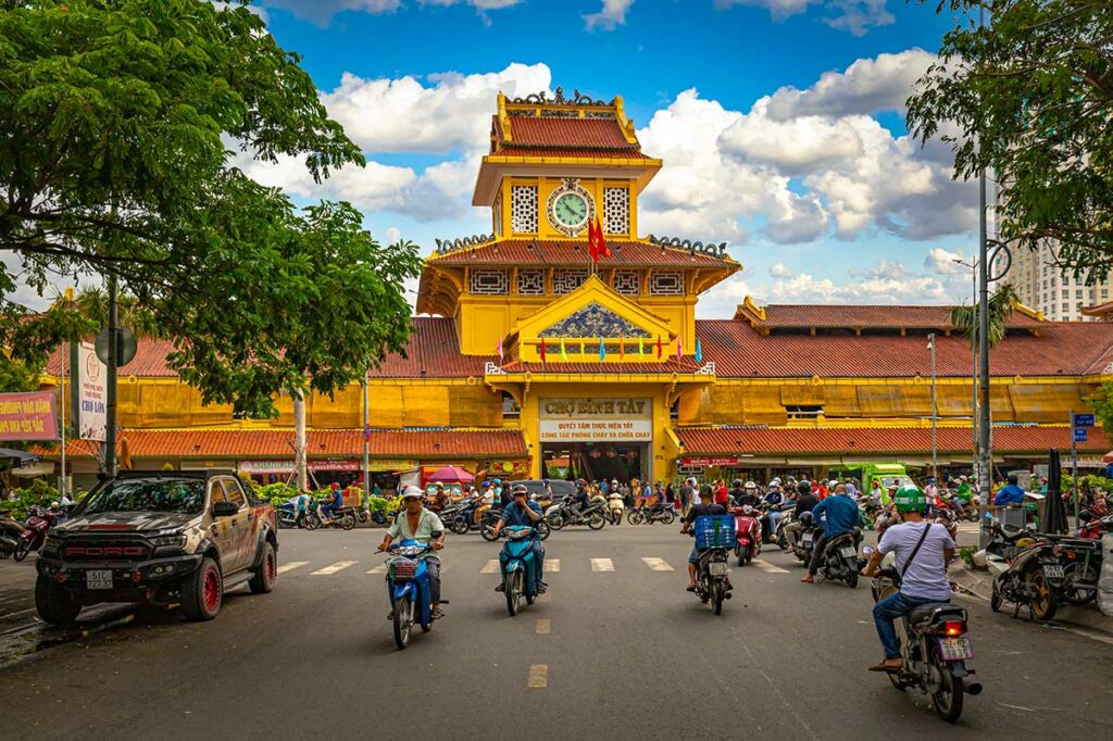 De hoofdgevel van Binh Tay Market in Chinatown van Ho Chi Minh City, gezien vanaf de straat met motorbikes en marktkramen.