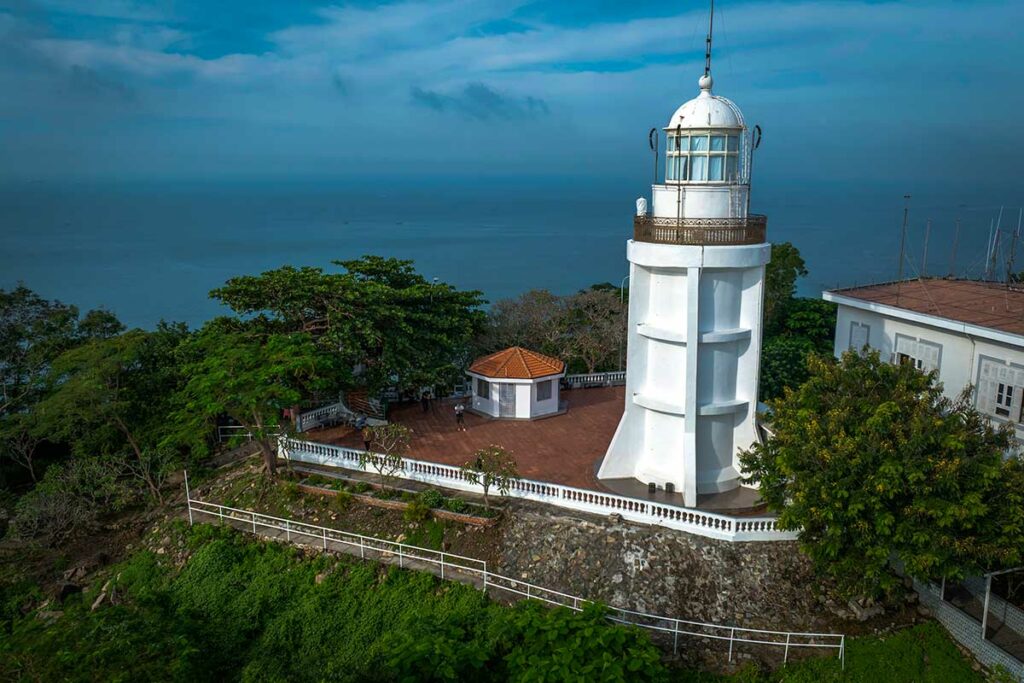Witte vuurtoren van Vung Tau op de heuvel, omringd door groen met uitzicht over zee