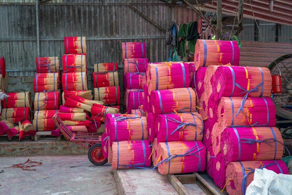 Opslagruimte in Quang Phu Cau wierookdorp met grote bundels roze en rode wierookstokjes, klaar voor verdere verwerking.