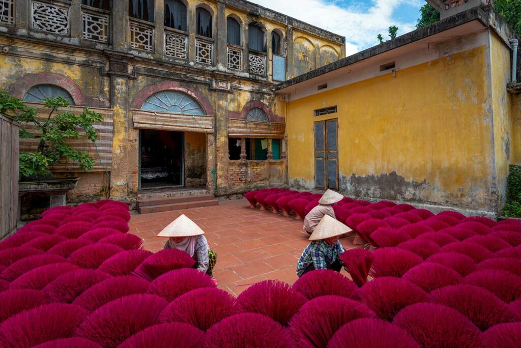 Bewoners werken tussen rijen rode wierookstokjes in Quang Phu Cau Incense Village, een traditioneel wierookdorp bij Hanoi.