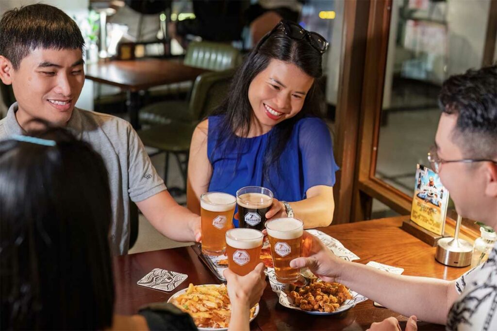 Groep vrienden proost met proefglazen Vietnamese craft beer bij 7 Bridges Brewing in Da Nang