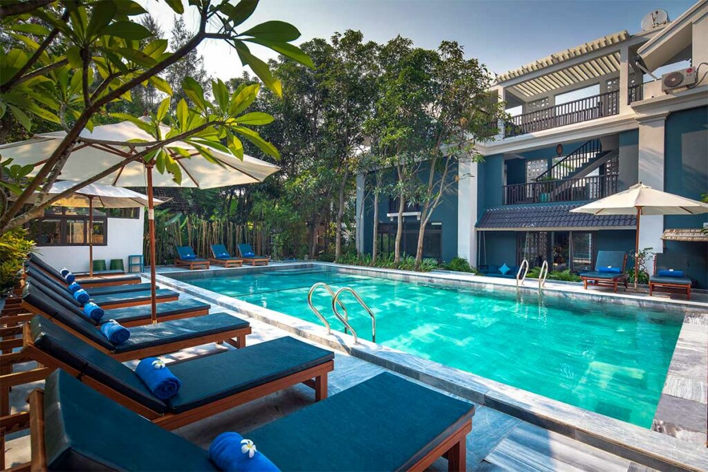 Zwembad van AIRA Boutique Hoi An Hotel & Villa bij An Bang Beach met ligbedden en tropische tuin