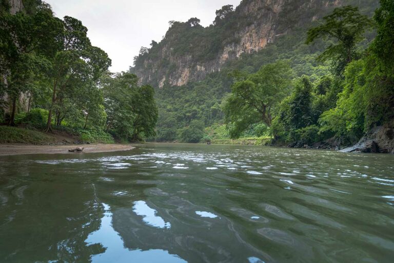 Rustige boottocht over Ba Be Lake in Ba Be National Park, met groene jungle, kalkstenen heuvels en een brede rivierarm in het noorden van Vietnam