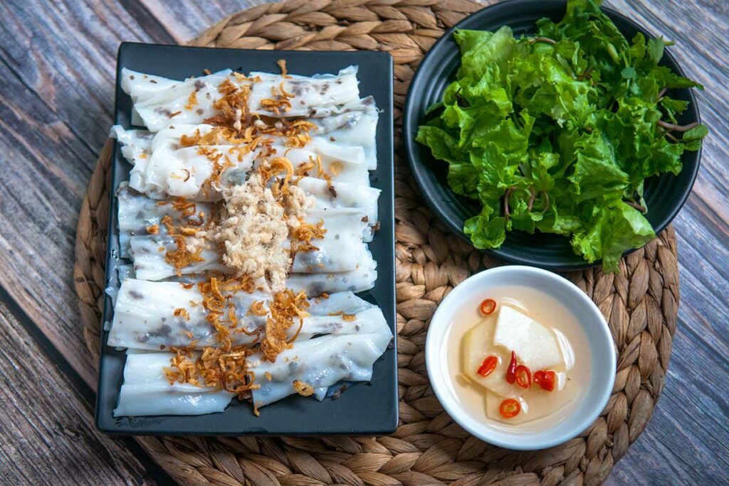 Bánh cuốn, dunne gestoomde rijstvellen gevuld met gehakt vlees, geserveerd met verse kruiden en lichte vissaus