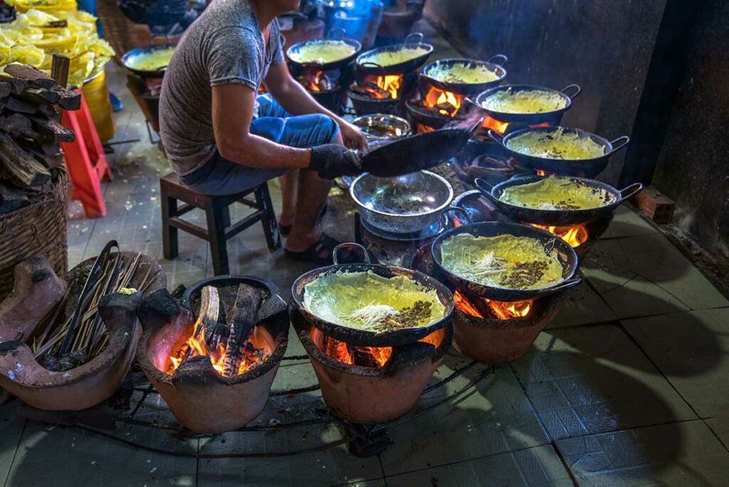 Bánh xèo, Vietnamese knapperige pannenkoek van rijstmeel en kurkuma, gevuld met taugé en vlees, bereid op houtskoolvuren